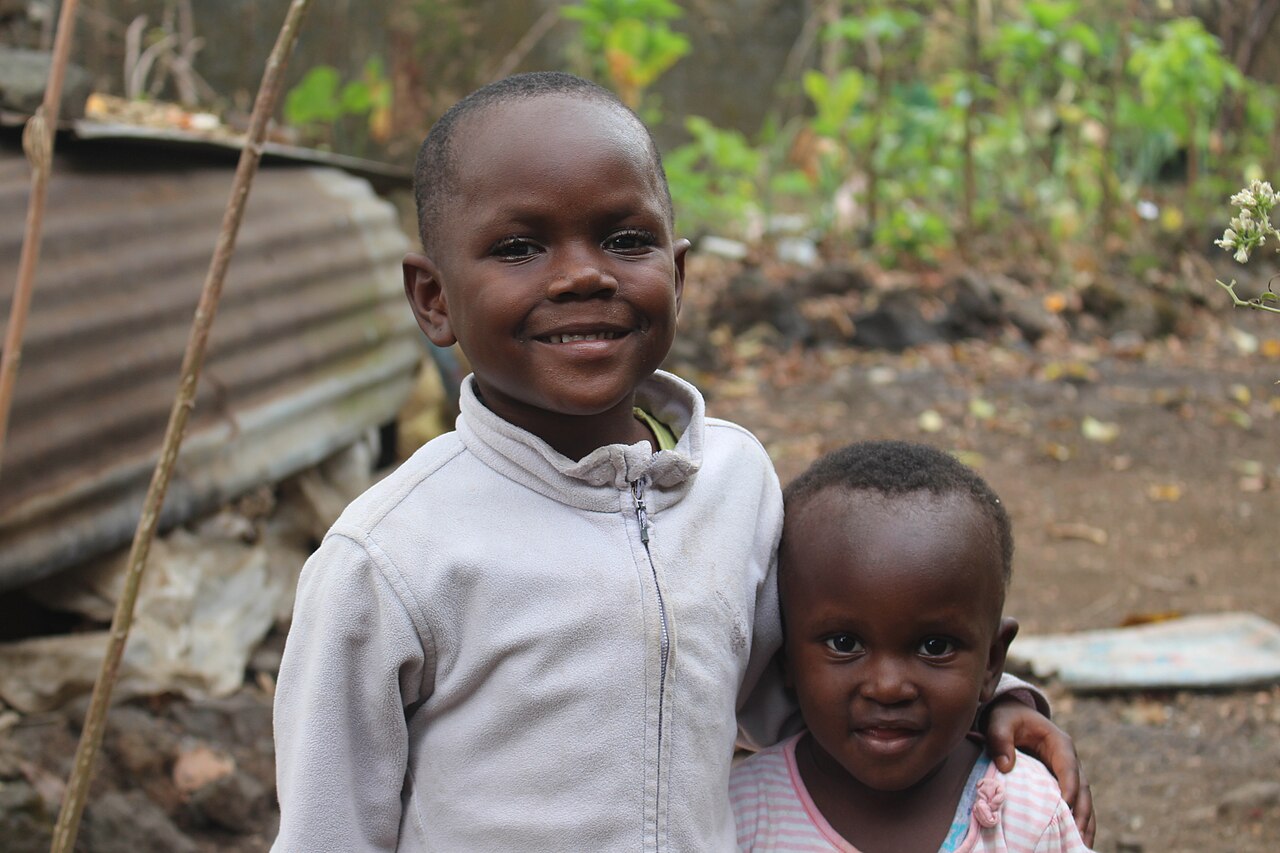 Two smiling children standing close together outdoors