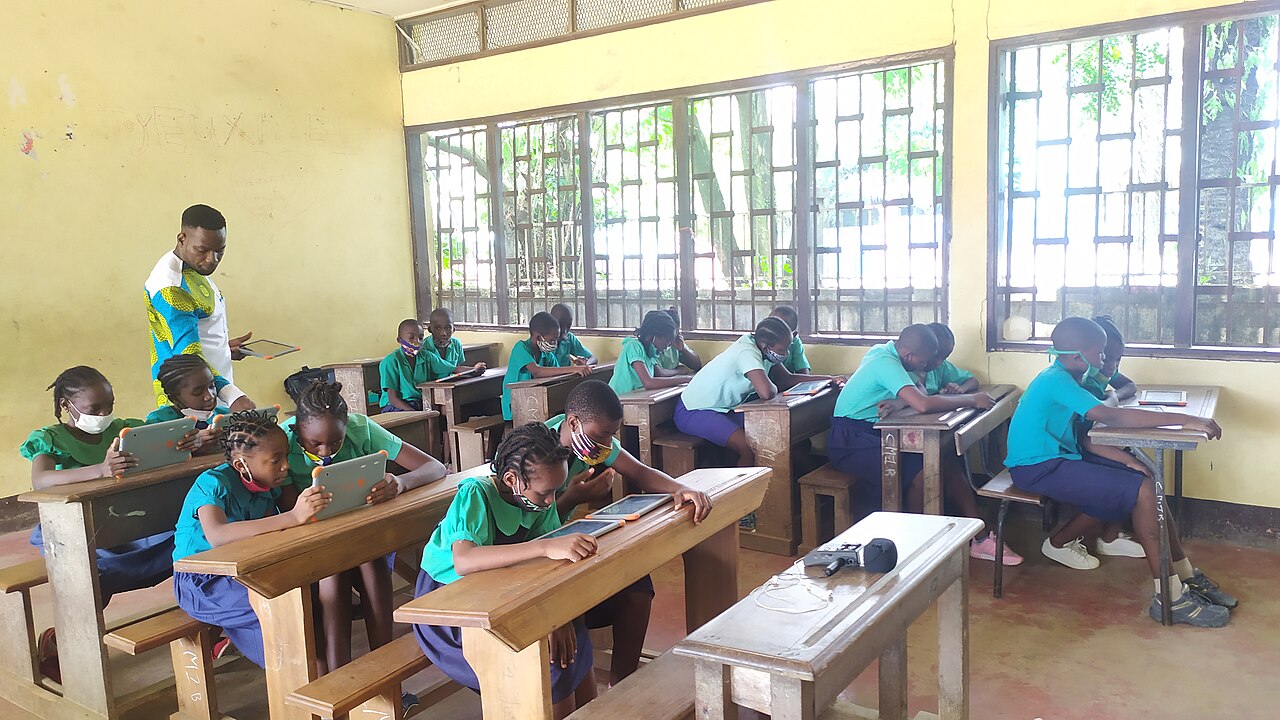 Pupils in a Cameroonian classroom working together on tablets with their teacher