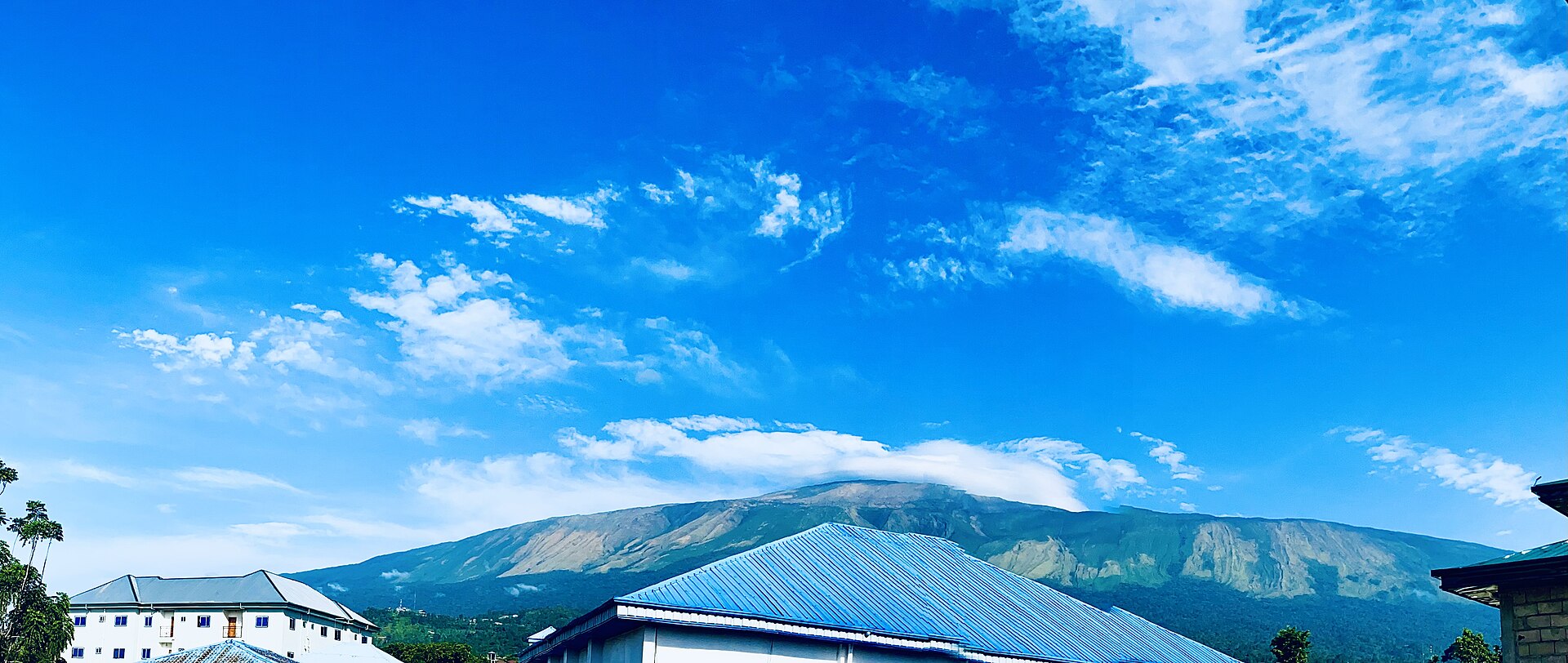Mount Cameroon rising above rooftops under a bright blue sky