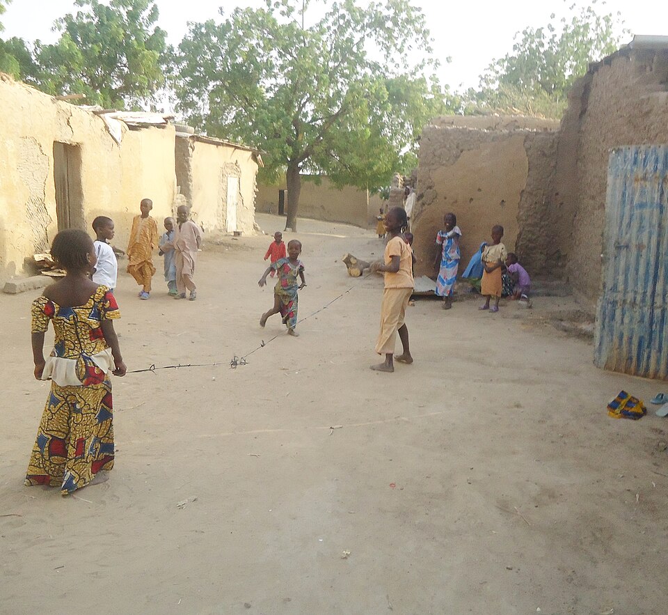 Children playing with a rope on a sandy village street in northern Cameroon